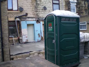 A green G&S portable toilet unit on a building site